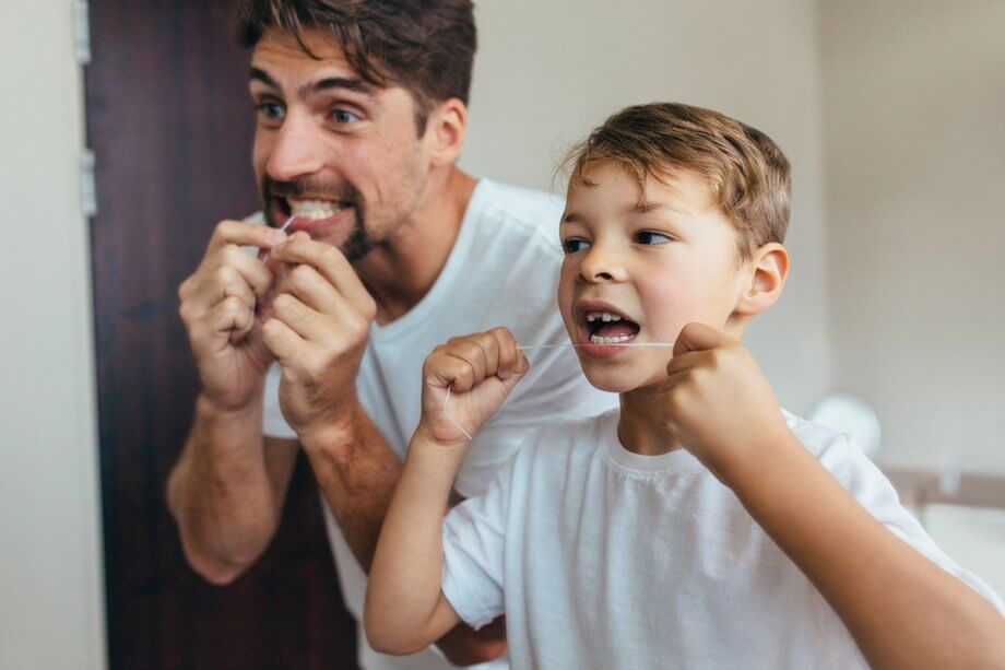 father and son flossing their teeth together