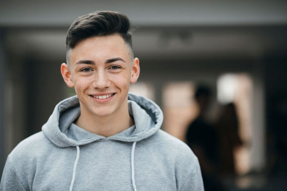 teen boy in grey sweatshirt, smiling